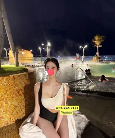 Woman in swimsuit sitting by a nighttime pool.