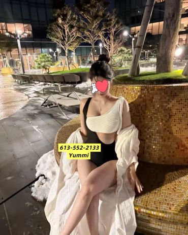 Woman in swimwear sitting by a pool at night.