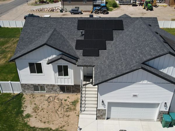 Modern house with solar panels on the roof and a white fence.
