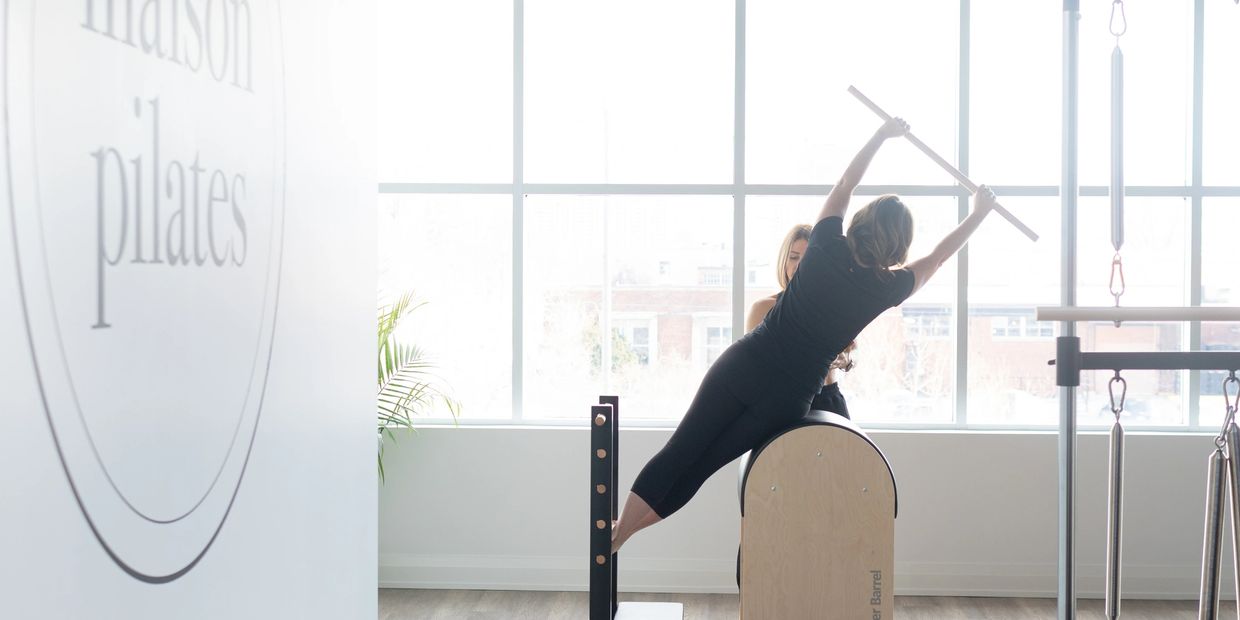 Pilates studio with Maison Pilates logo and a woman exercising in the background