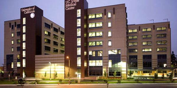 UC Irvine Medical Center building at dusk with lights on.