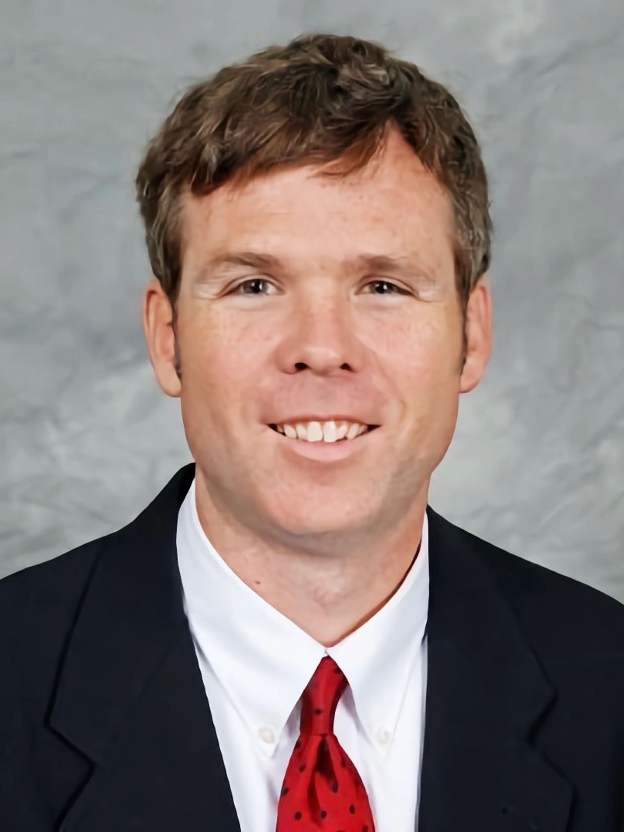 Man in business attire smiling for a portrait.