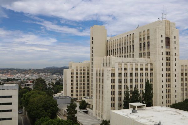 A large beige multi-story building under a partly cloudy sky.