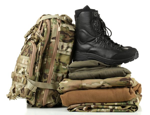 Military backpack, boots, and folded camouflage clothing on white background.