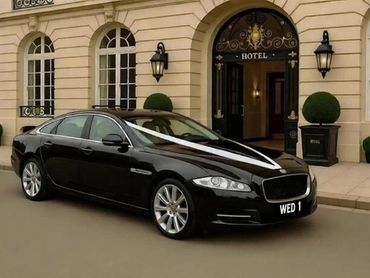Black luxury car decorated for a wedding outside a hotel.