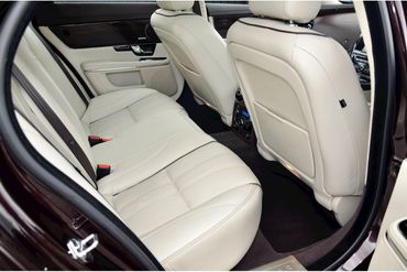 Luxurious beige leather backseat interior of a Jaguar car.