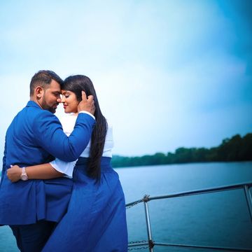 Couple embracing tenderly on a boat by the water with a serene sky.