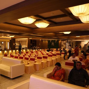 Elegant banquet hall with gold and red decorated chairs and warm lighting.