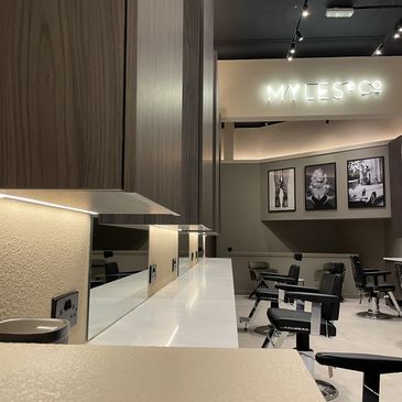 Modern barbershop interior with sleek design and stylish black chairs.