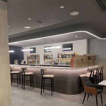 Modern bar area with stools and ambient lighting.