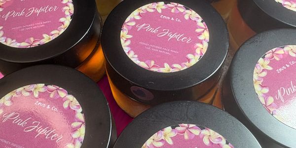 Jars of Pink Jupiter honey-infused face masks by Zeus & Co. on a pink background.