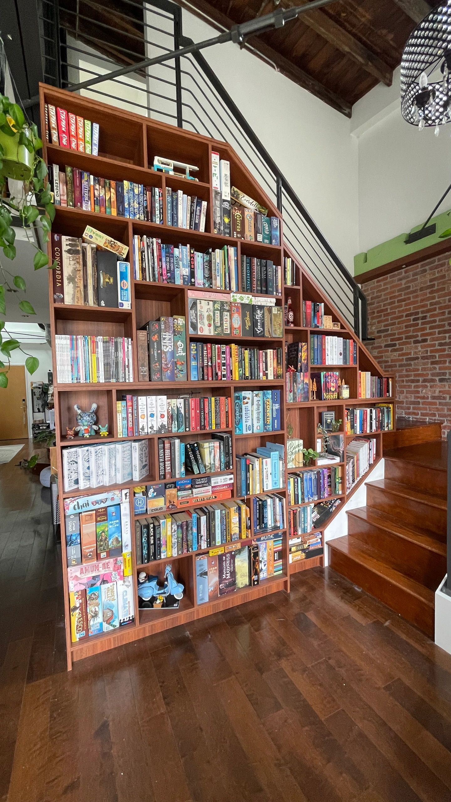 Bookshelf built under stairs filled with books and board games.