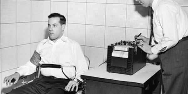 Man undergoes polygraph test while technician records data.