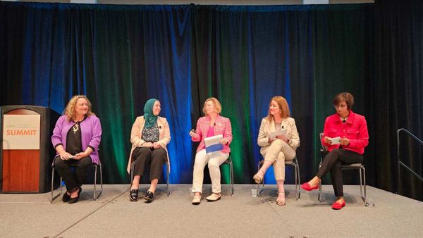 Five women seated on a stage panel at the Women in Manufacturing Summit.