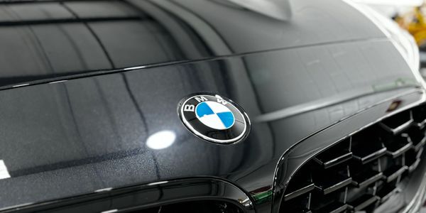 Close-up of BMW emblem on black car hood with grille.