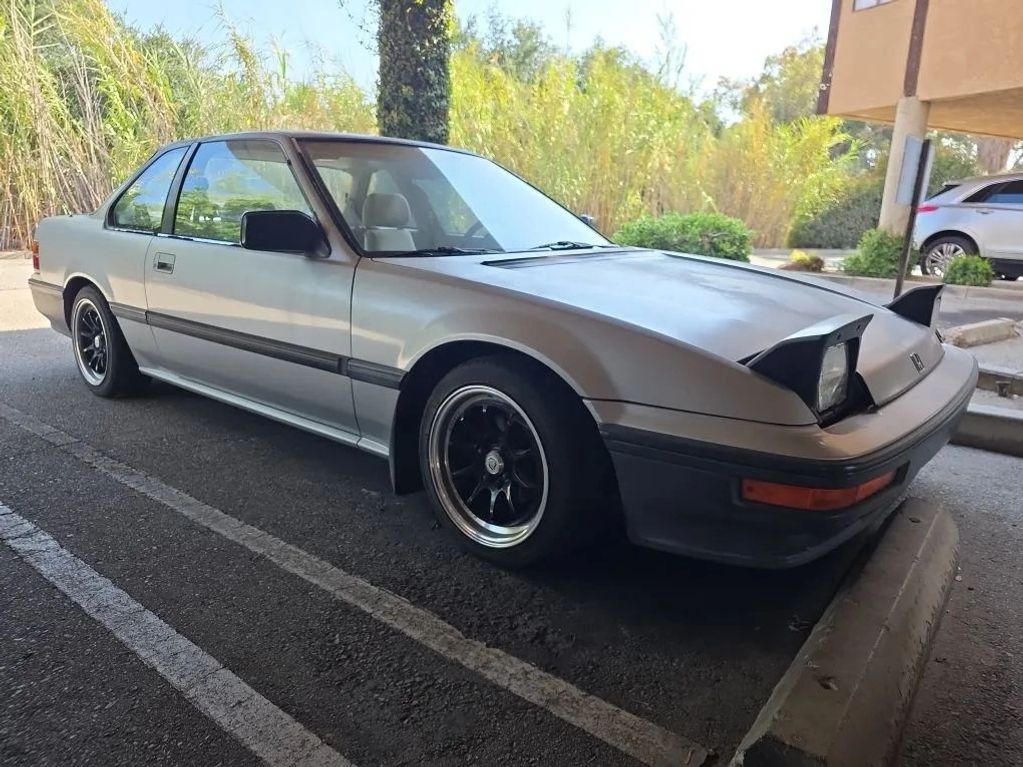 Classic silver coupe with pop-up headlights parked outdoors.