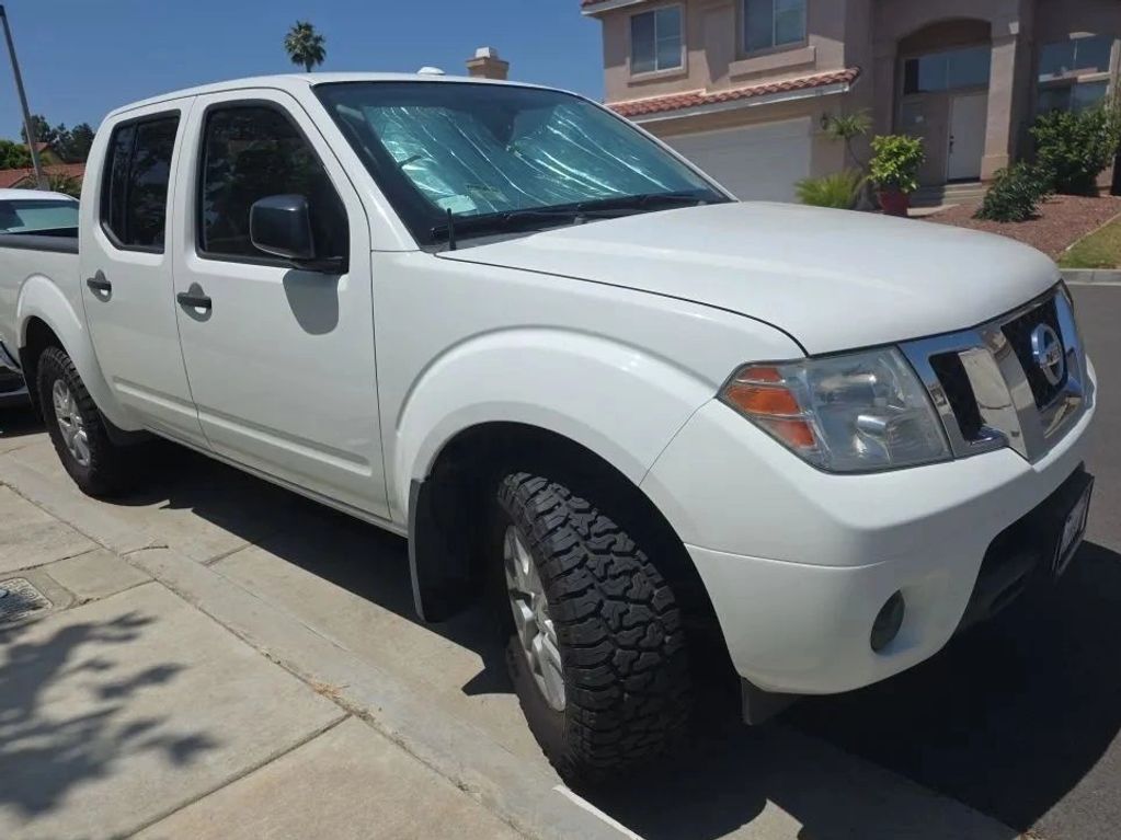 White Nissan pickup truck parked on a residential street on a sunny day.