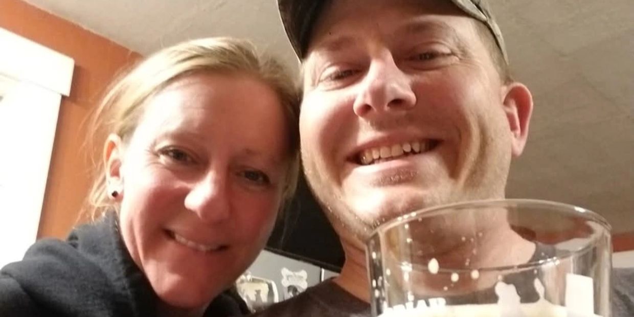 Smiling couple taking a close-up selfie indoors with a drink.