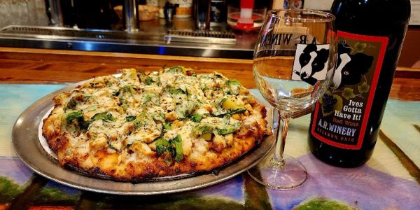 A delicious pizza with a wine bottle and glass on a colorful table.