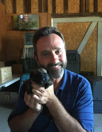 a man holding a puppy and smiling 