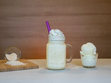 A creamy milkshake with whipped cream in a mason jar with a purple straw.