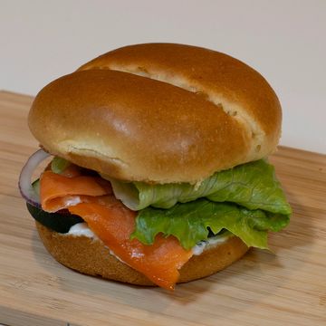 A fresh sandwich with smoked salmon and lettuce on a wooden surface.