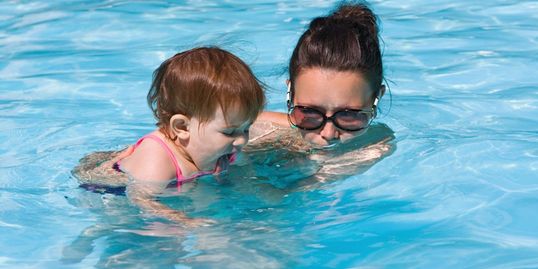Mom swimming with baby. She's happy with her pool service.
