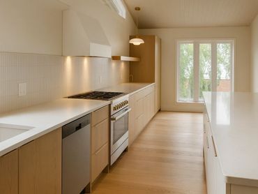 Modern kitchen with light wood cabinets and white countertops.