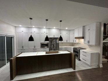 Modern kitchen with white cabinets, black pendant lights, and a wooden island.