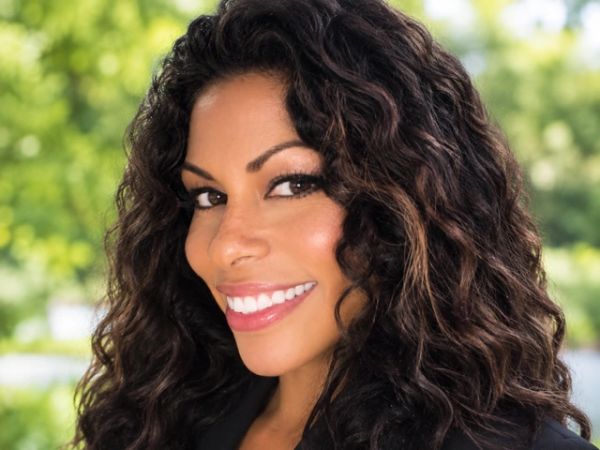 Smiling woman with long curly hair outdoors.