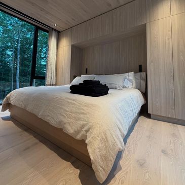 Cozy modern bedroom with wooden accents and large window.