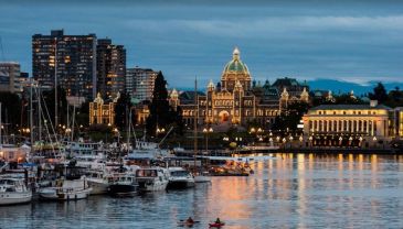 Evening cityscape with boats docked on calm water.