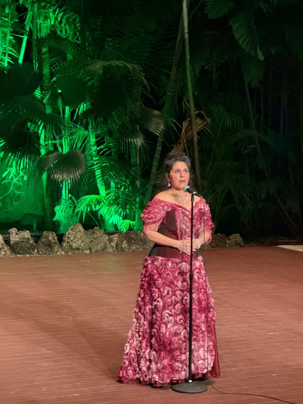 Woman singing on stage outdoors at night.