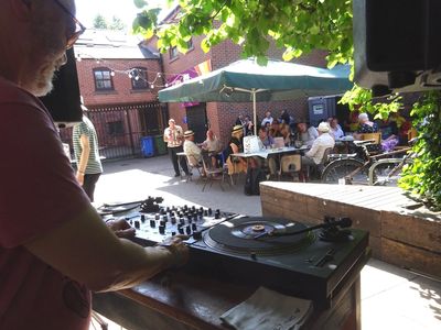 DJ playing vinyl at an outdoor cafe.