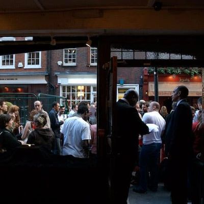 People gathered outside a building, viewed from inside through an open door.