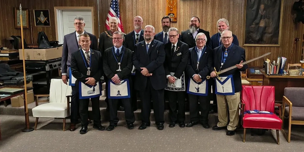 A group of men in formal attire with Masonic aprons posing indoors.