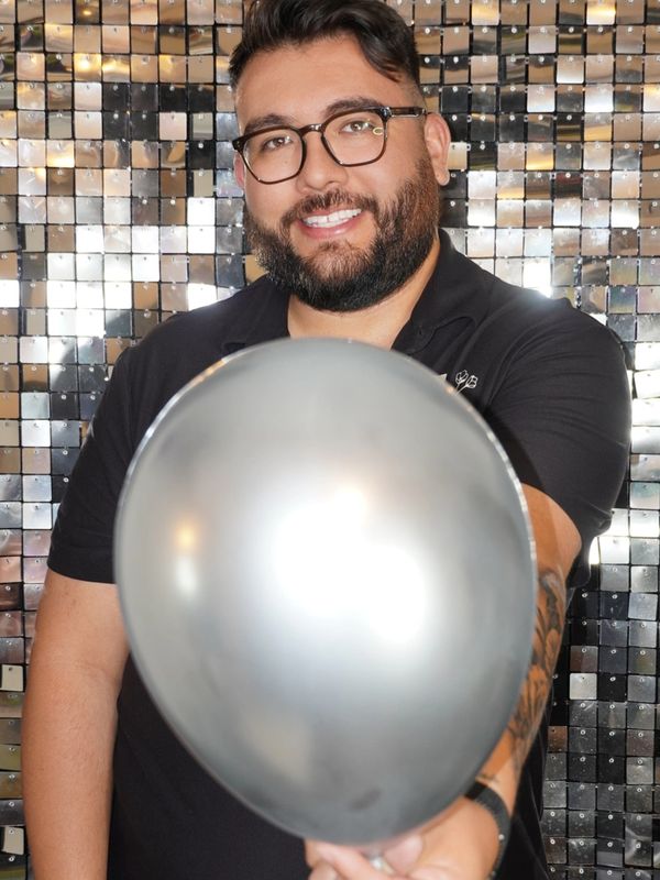 Smiling man with glasses holding a silver balloon.