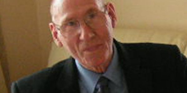 Elderly man in glasses wearing a suit and tie.