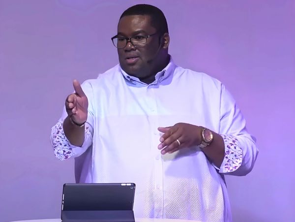 Man in glasses speaking with an iPad in front of him.
