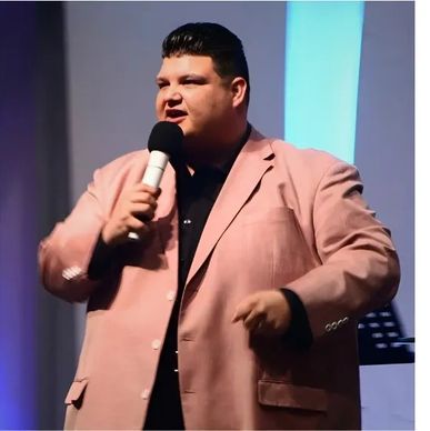 Man speaking on stage with a microphone.