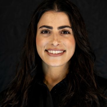 Smiling woman with long dark hair against a black background.