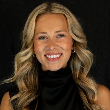 Smiling woman with wavy blonde hair and gold hoop earrings against a black background.