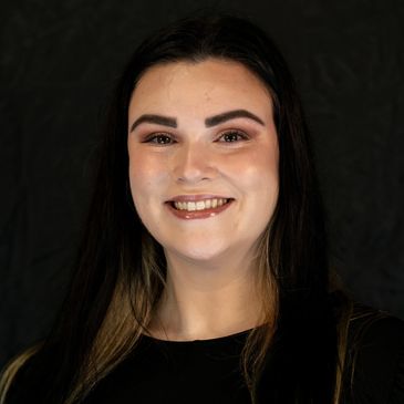 Smiling woman with dark hair against a black background.