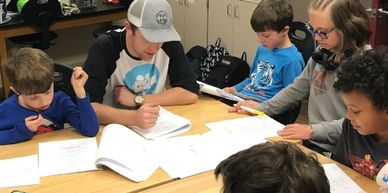 A group of children and an adult working together on schoolwork.