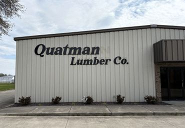 Front view of Quatman Lumber Co. building under a cloudy sky.
