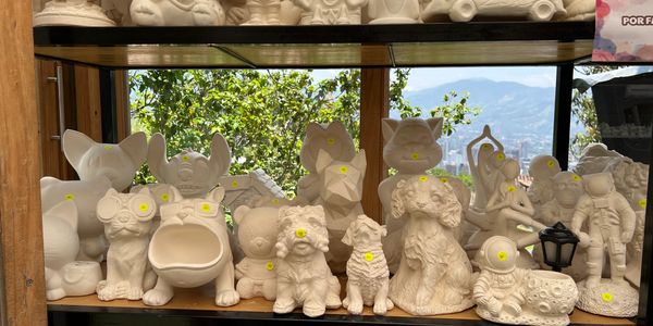 Unpainted ceramic animal and character figurines displayed on a shelf.