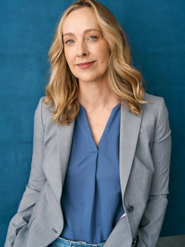 Confident woman in grey blazer and blue top.
