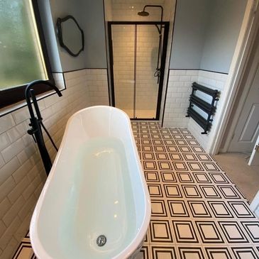 Modern bathroom with a freestanding tub and geometric floor tiles.