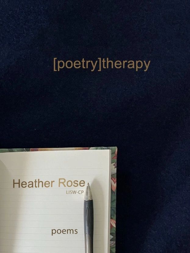 A poetry book by Heather Rose with a pen on it.