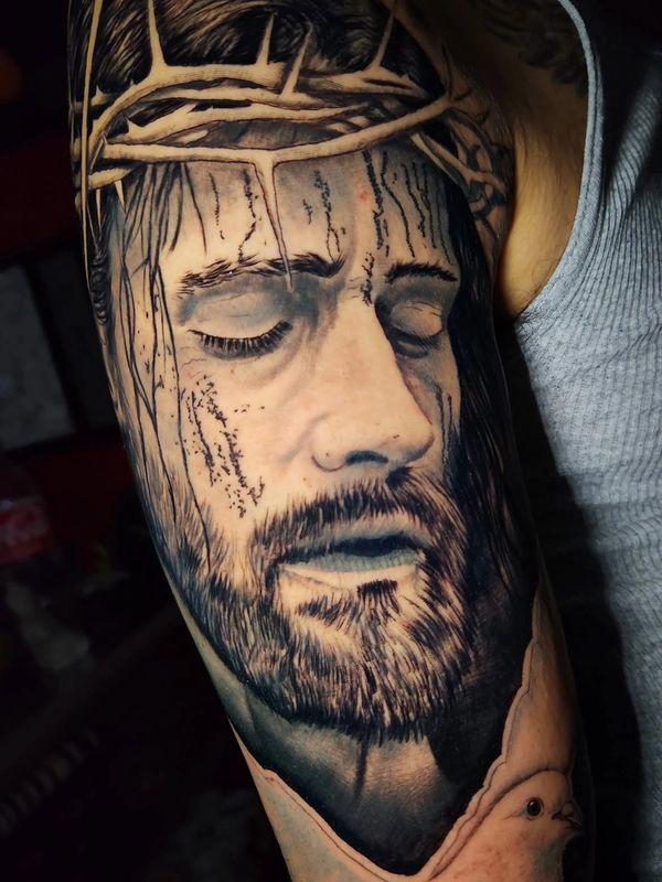 Tatuaje realista de Jesús con corona de espinas y paloma.